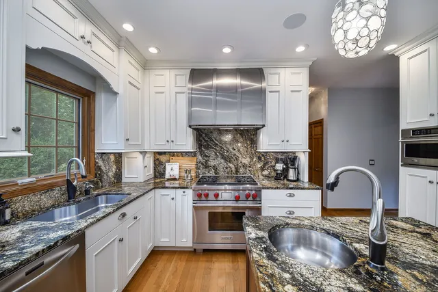 a kitchen with kitchen island granite countertop a stove a sink a refrigerator wooden floor and cabinets