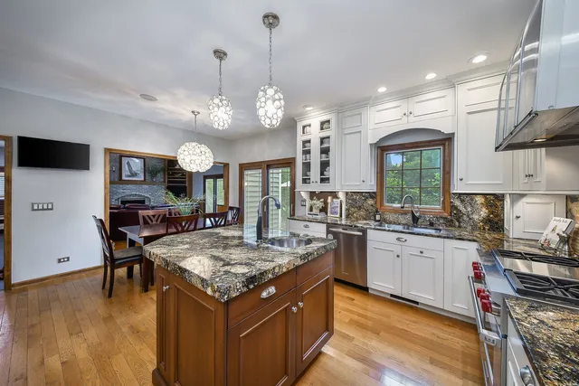 a kitchen with stainless steel appliances granite countertop stove a sink dishwasher and a refrigerator with wooden floor
