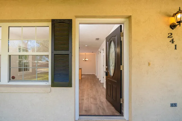 a view of a hallway with wooden floor and a bathroom
