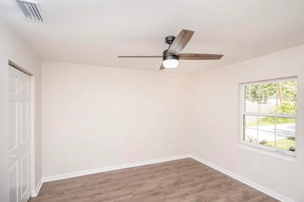 an empty room with a window and a ceiling fan