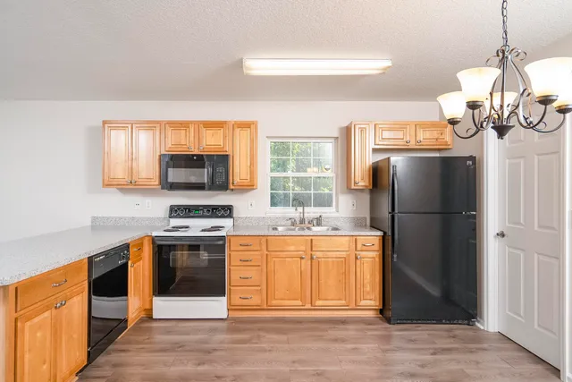 a kitchen with stainless steel appliances granite countertop a refrigerator a stove a sink dishwasher and a refrigerator with wooden floor