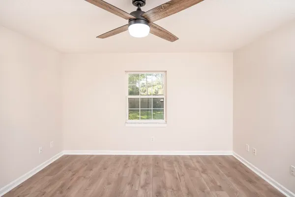an empty room with a window and a fan