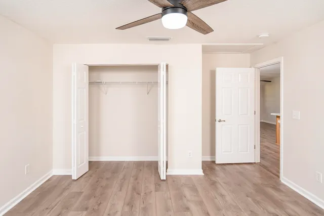 an empty room with a hardwood and ceiling fan