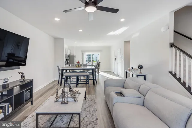 a living room with furniture a flat screen tv and kitchen view