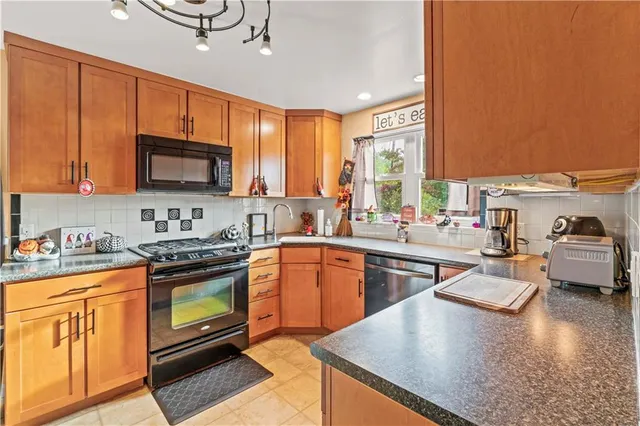 a kitchen with stainless steel appliances granite countertop a stove top oven a sink dishwasher a dining table and chairs with wooden floor