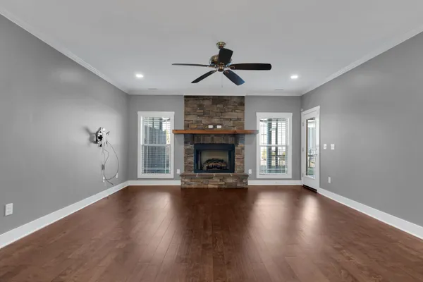 a view of an empty room with wooden floor fireplace and a window