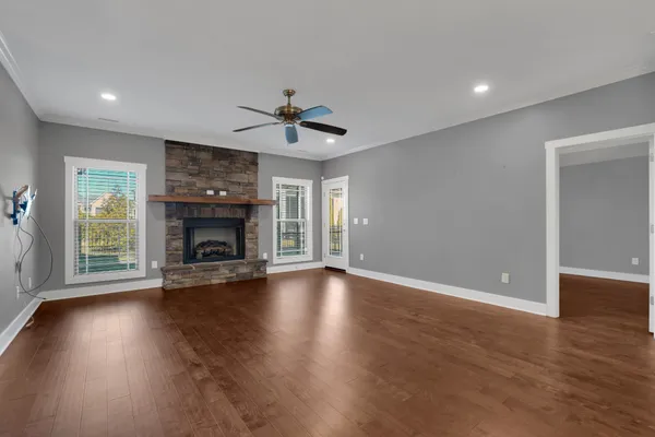 a view of an empty room with wooden floor and a fireplace