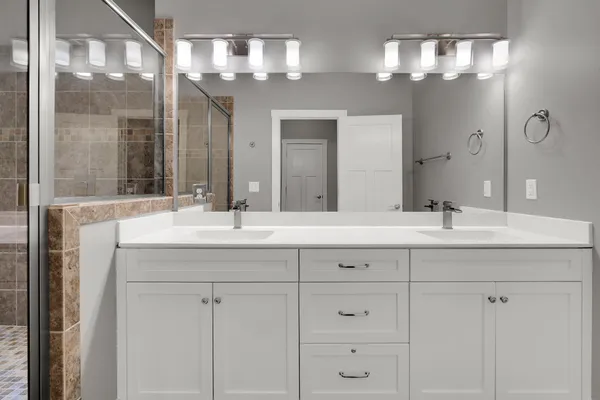 a bathroom with double vanity and a mirror