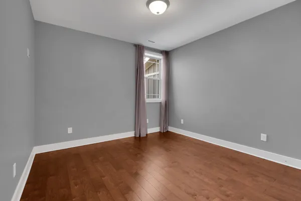 a view of an empty room with wooden floor and windows