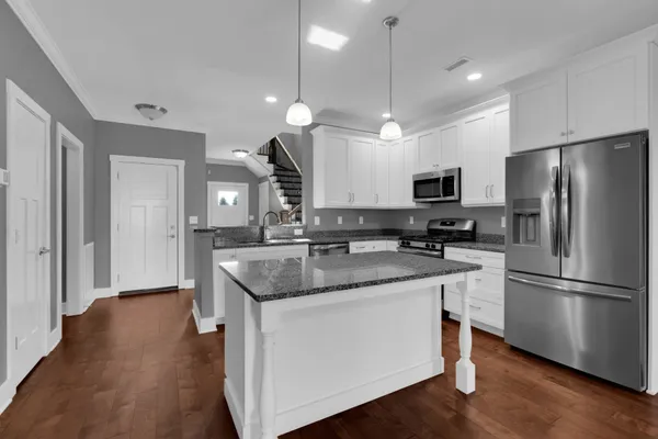a kitchen with a sink stainless steel appliances and wooden floor
