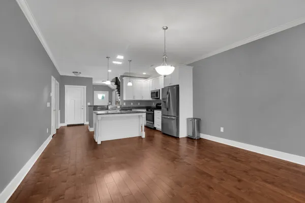 a large kitchen with white cabinets stainless steel appliances a chimney and a chandelier