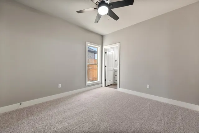 a view of an empty room and chandelier fan