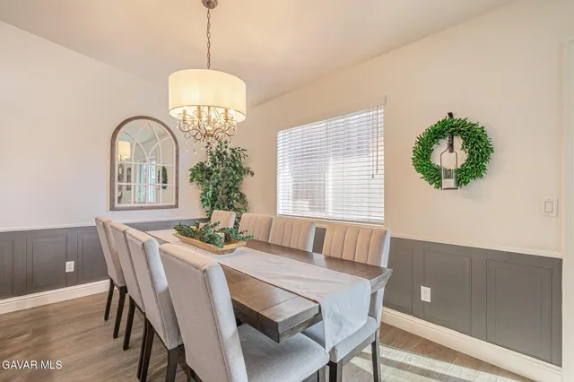 a kitchen with stainless steel appliances granite countertop a dining table chairs refrigerator and sink