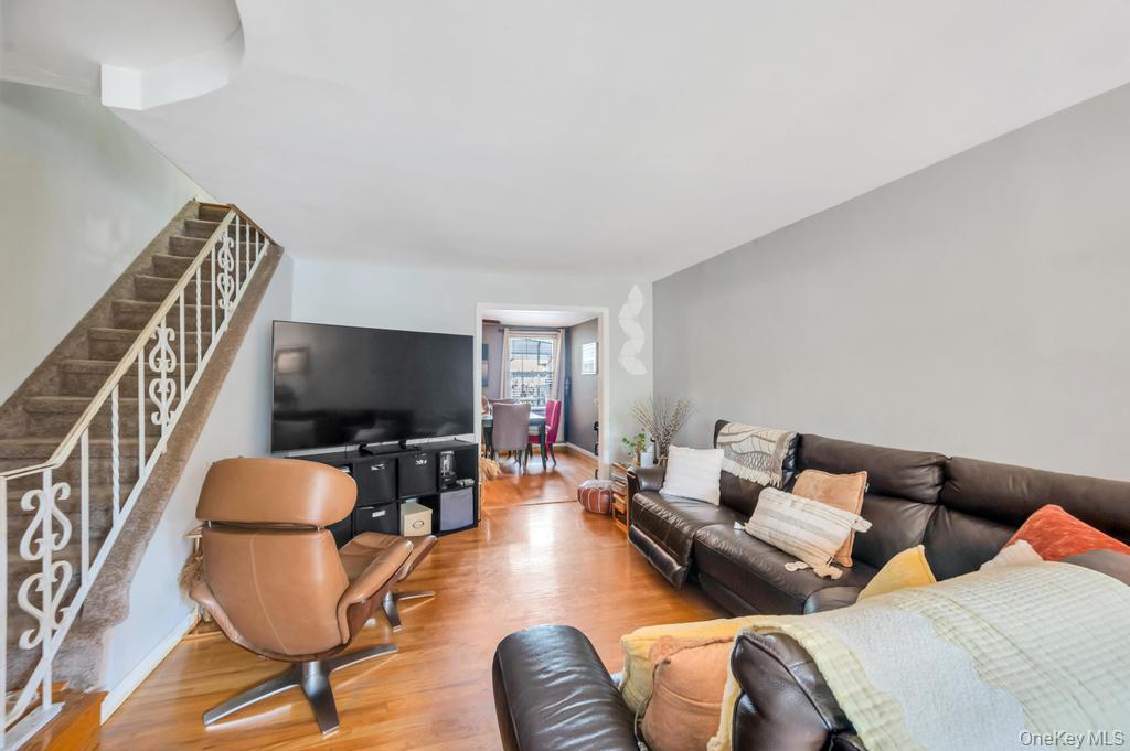89-13 84th Street Queens, NY 11421 - Photo 13 of 34 Living area featuring wood-finish flooring, a neutral wall color, and a carpeted staircase with decorative white railings