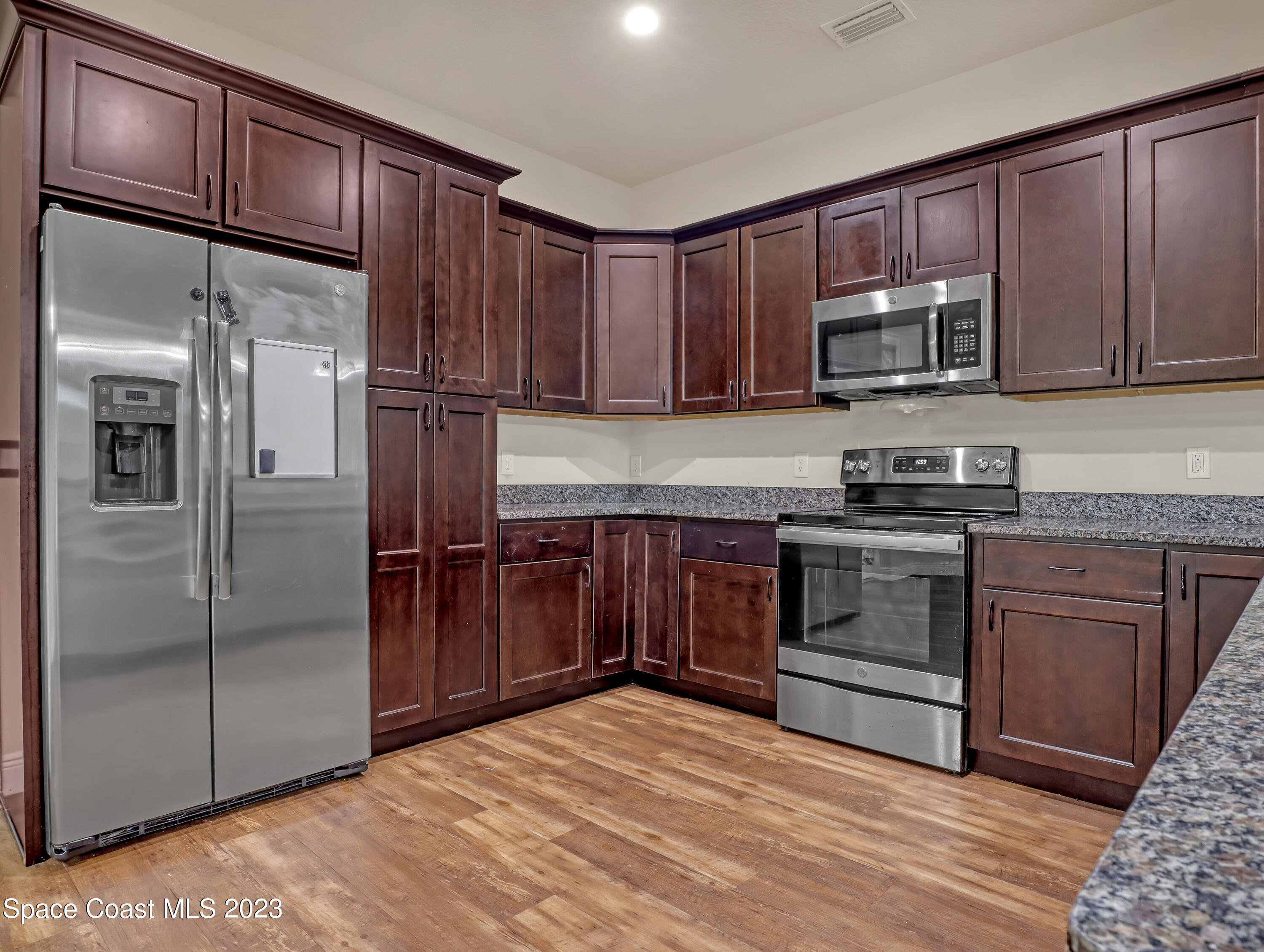 1310 Gaucho Road Southwest Palm Bay, FL 32908 - Photo 13 of 32 a kitchen with stainless steel appliances granite countertop a refrigerator stove and sink with wooden cabinets