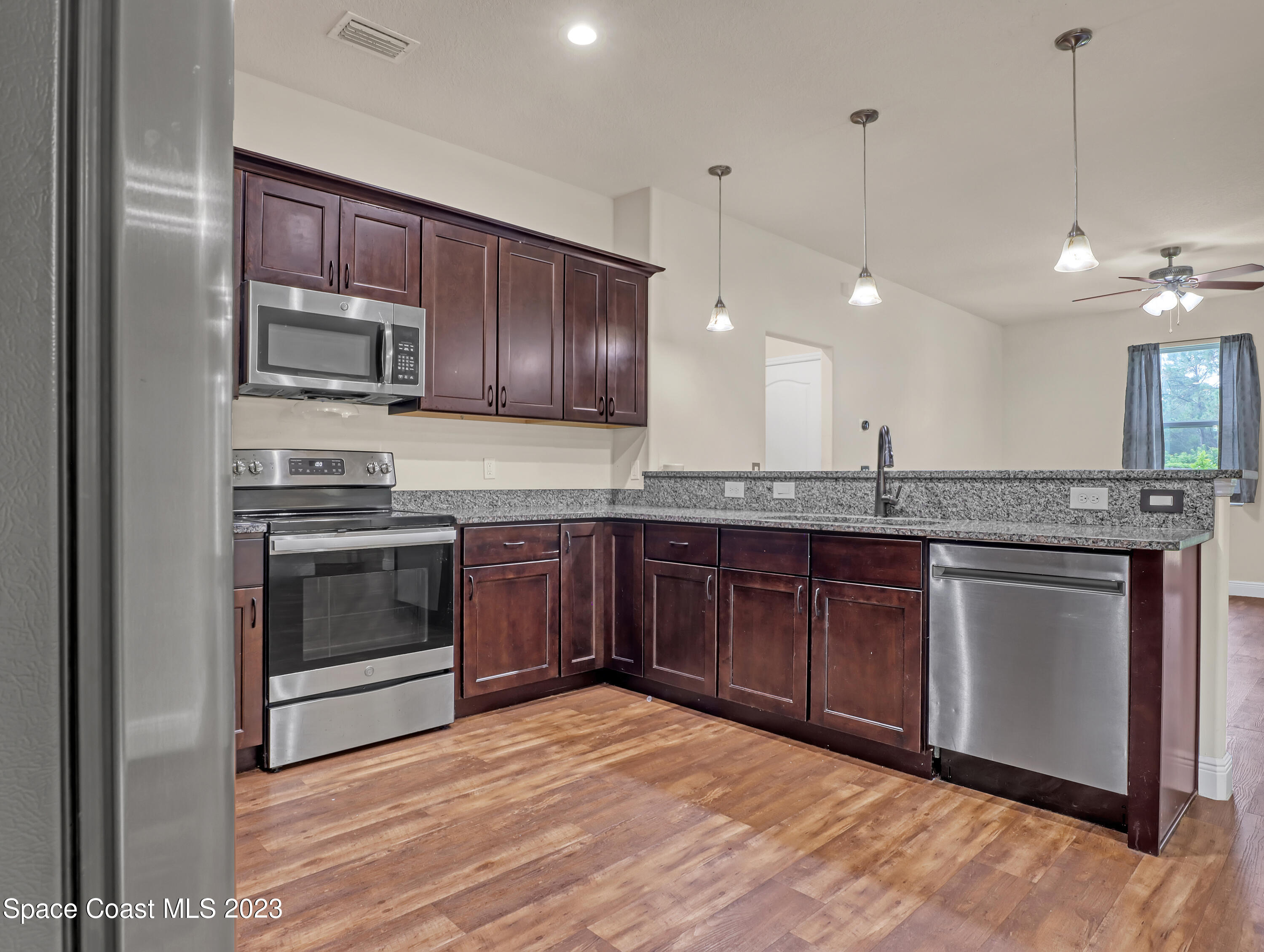 1310 Gaucho Road Southwest Palm Bay, FL 32908 - Photo 14 of 32 a kitchen with stainless steel appliances granite countertop a stove a sink and a microwave
