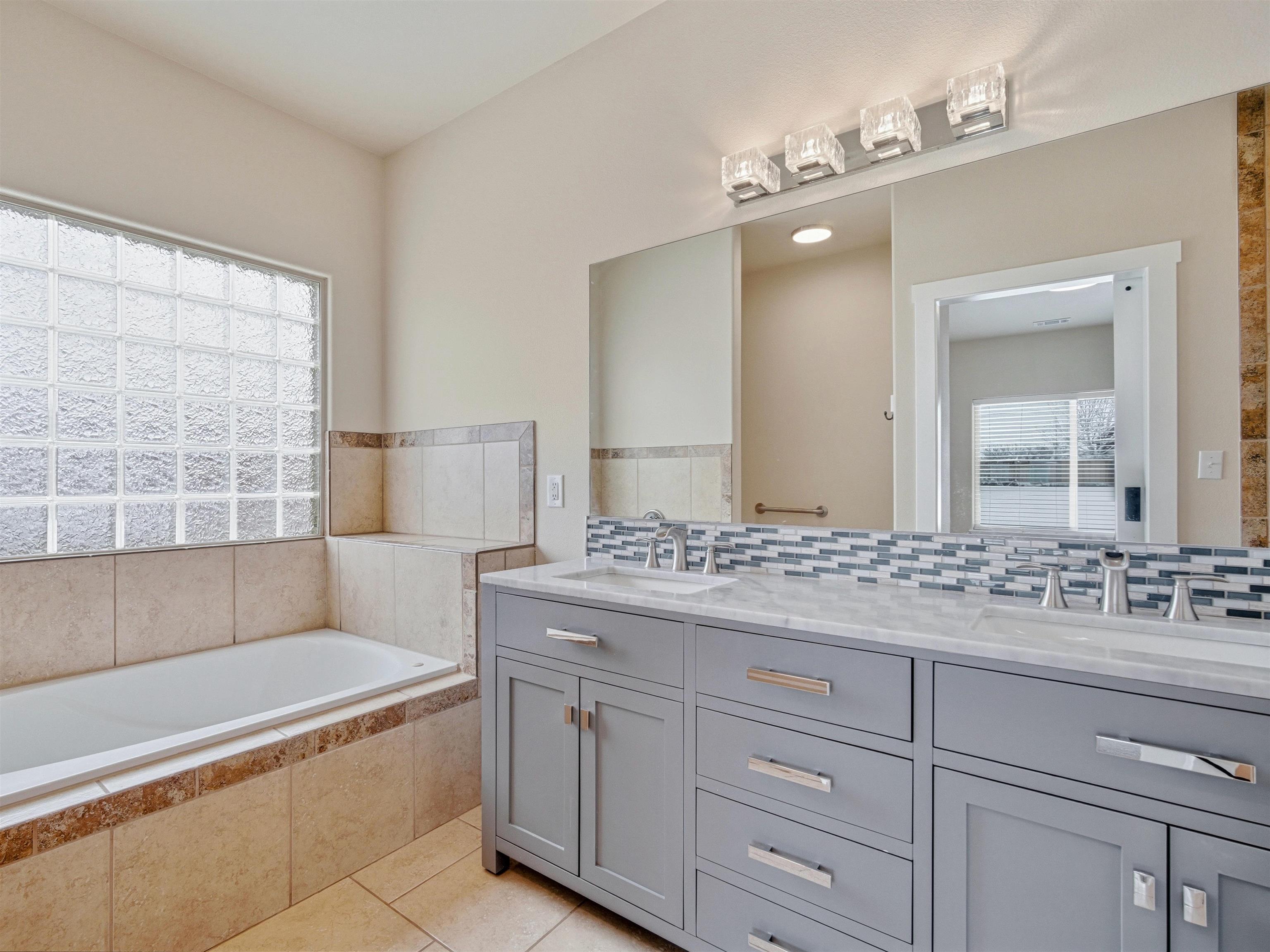 1850 Golden Ranch Road Fruita, CO 81521 - Photo 19 of 39 a bathroom with a granite countertop sink a mirror and a bathtub