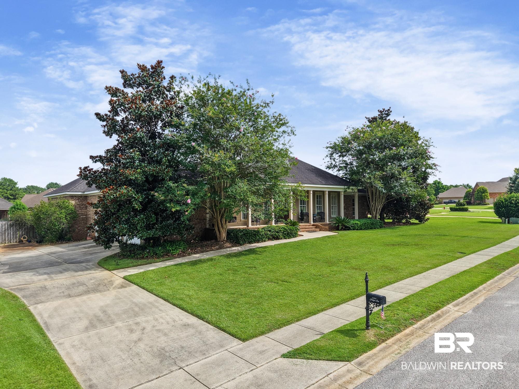 11261 Halcyon Loop Daphne, AL 36526 - Photo 4 of 41 Brick exterior residence featuring a covered front porch with white columns, a concrete driveway, and a concrete sidewalk