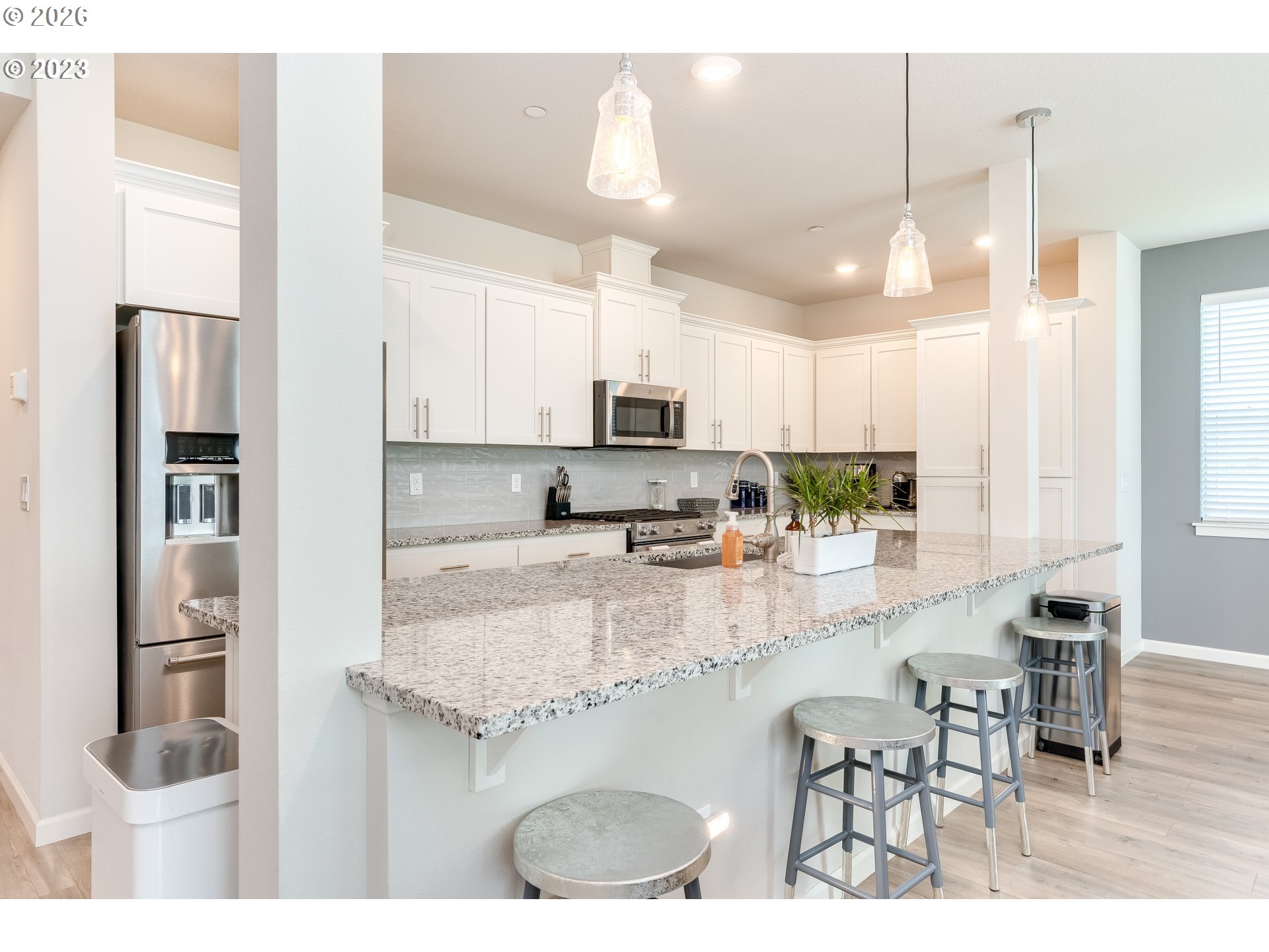 6150 North 86th Avenue Camas, WA 98607 - Photo 20 of 41 a kitchen with stainless steel appliances kitchen island granite countertop a refrigerator a stove a sink a dining table and chairs with wooden floor