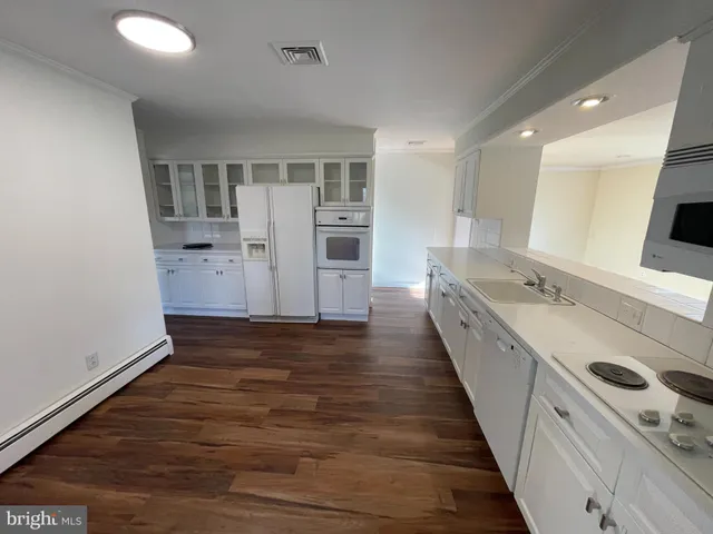 a view of a kitchen with a sink and dishwasher with wooden floor