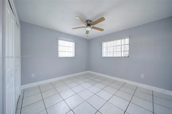 an empty room with windows and ceiling fan