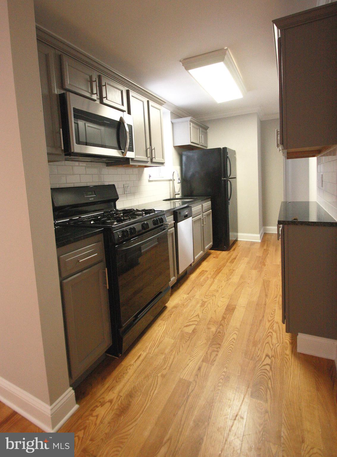 763 South 15th Street, Unit 2 Philadelphia, PA 19146 - Photo 4 of 12 a kitchen with stainless steel appliances granite countertop a stove top oven a sink dishwasher a refrigerator and a microwave