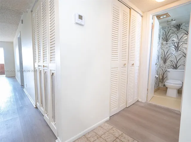 a view of a hallway with wooden floor and a bathroom