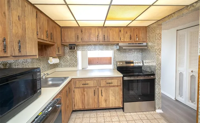 a kitchen with stainless steel appliances granite countertop a stove a sink and a microwave