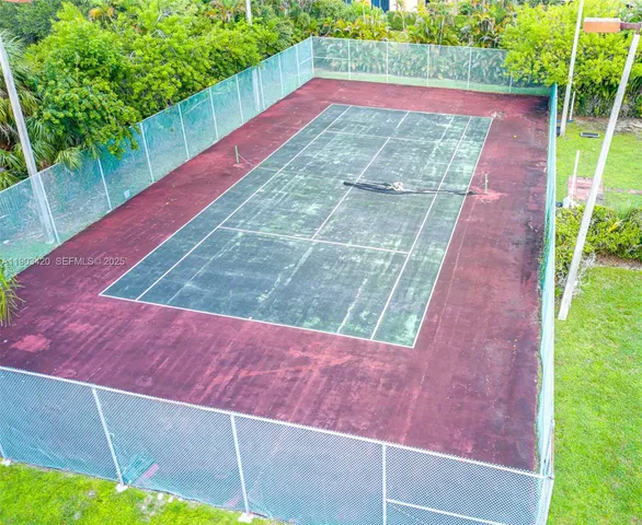 a view of a pool with lawn chairs plants and large trees