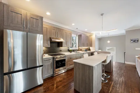 a kitchen with stainless steel appliances a stove a sink a refrigerator a center island and a refrigerator
