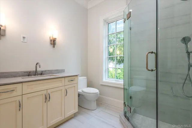 a bathroom with a granite countertop toilet a sink and a window