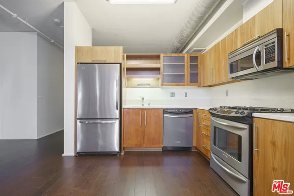 a kitchen with a refrigerator stove and wooden floor