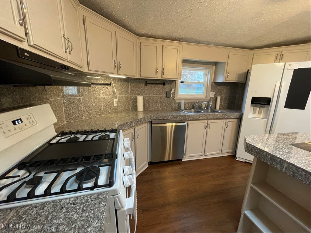 Kitchen featuring dishwasher, sink, dark wood-type flooring, white range, and fridge