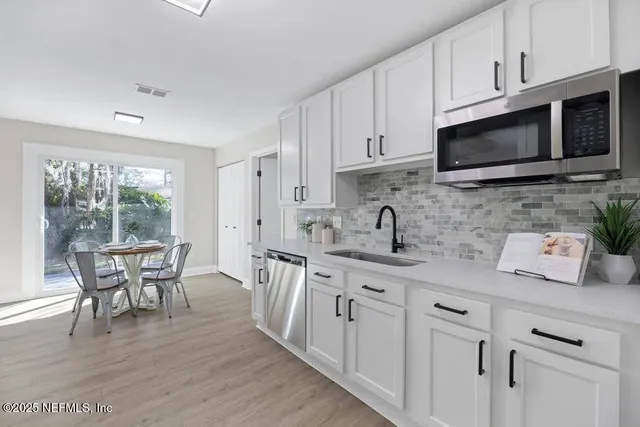 a kitchen with stainless steel appliances granite countertop a stove a sink a microwave and white cabinets