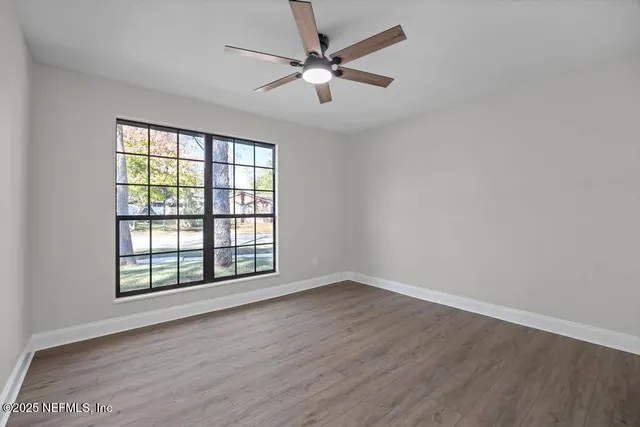an empty room with wooden floor and windows