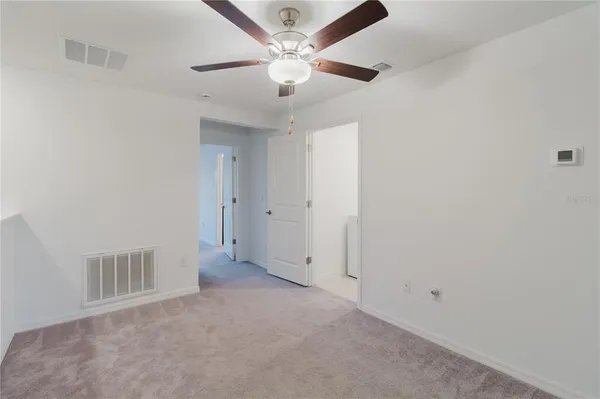 an empty room with a ceiling fan and window