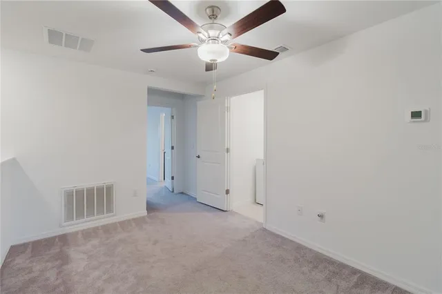 an empty room with a ceiling fan and window