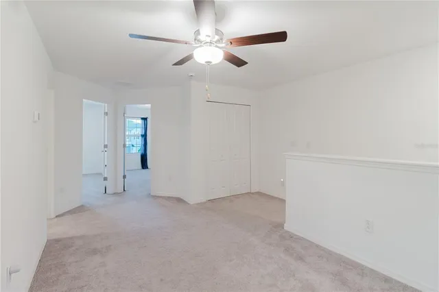 an empty room with closet and a ceiling fan