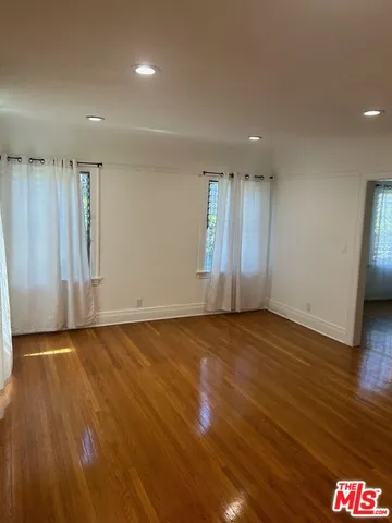 a view of an empty room with wooden floor and closet