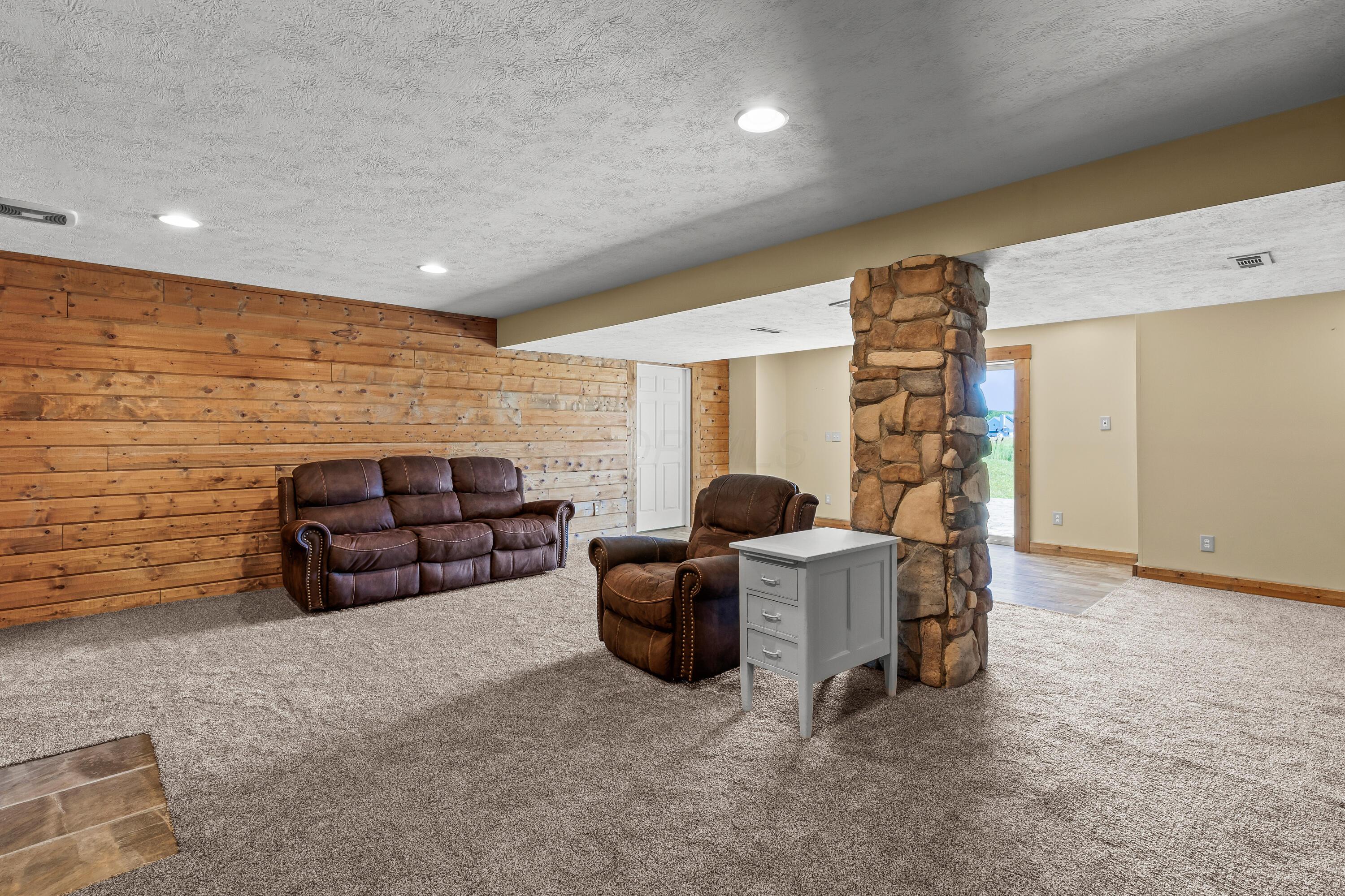 3582 Panhandle Road Delaware, OH 43015 - Photo 39 of 65 • New light sand carpet ~ 2024 • Ivory painted & wood planked walls • Gas fireplace with mantle • Built-in bookcases • Hidden door to private room • Luxury vinyl plank flooring at door landing • Double sliding doors to patio