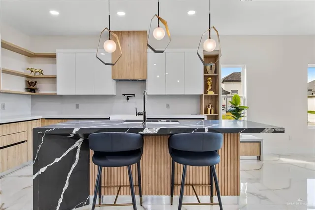 a kitchen with stainless steel appliances granite countertop a sink a stove a dining table and chairs with wooden floor