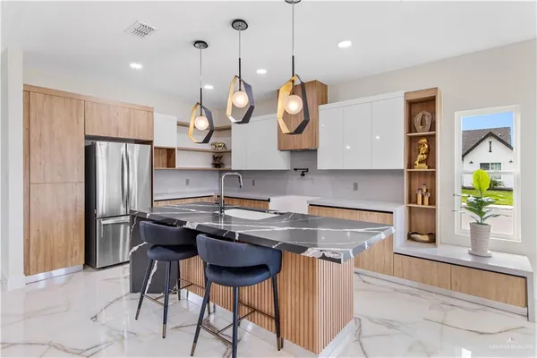 a kitchen with stainless steel appliances granite countertop a sink a stove a refrigerator cabinets and living room view