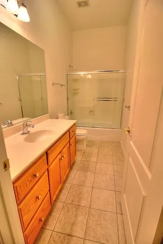 a bathroom with a granite countertop sink a toilet and a shower