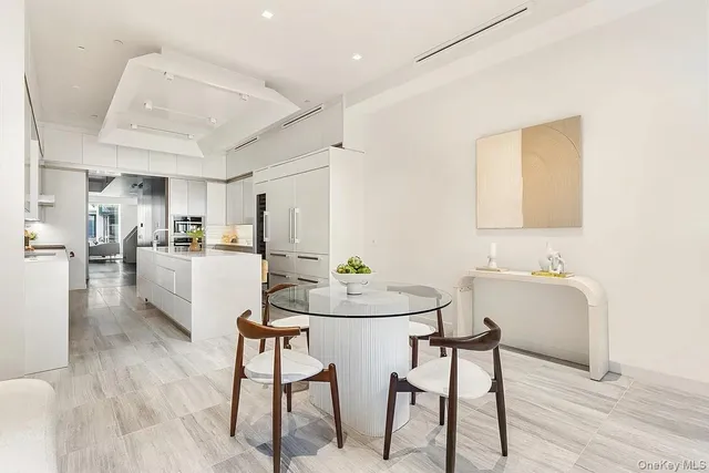 a kitchen with stainless steel appliances kitchen island granite countertop a dining table chairs and a refrigerator