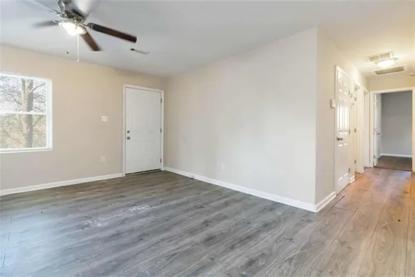 a view of an empty room with wooden floor and a window