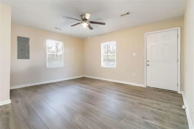 a view of an empty room with wooden floor and a window