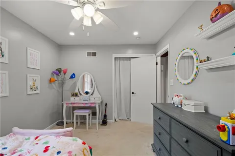 a bedroom with a bed a dresser and a chandelier