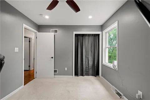 a view of an empty room with window and closet area