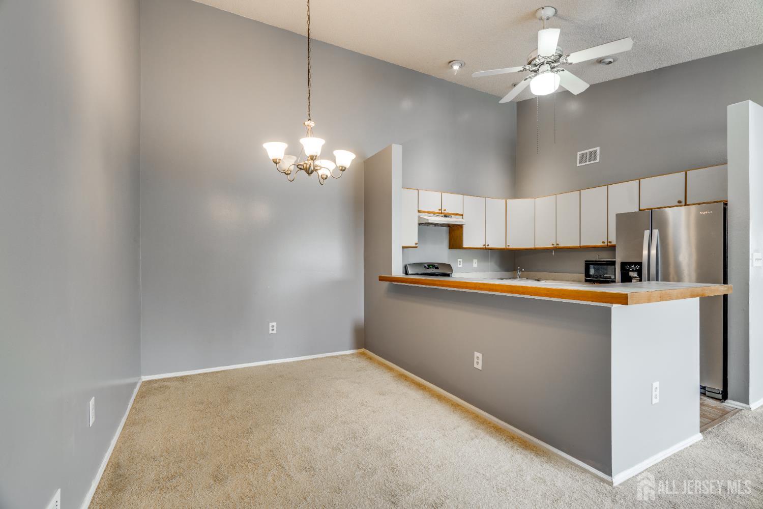 304 Wimbeldon Court North Brunswick, NJ 08902 - Photo 5 of 19 a kitchen with kitchen island white cabinets appliances and a chandelier