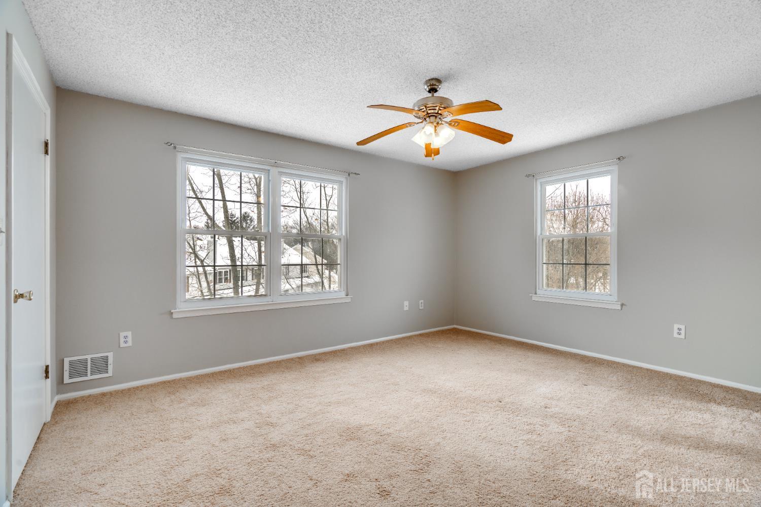 304 Wimbeldon Court North Brunswick, NJ 08902 - Photo 7 of 19 an empty room with windows and chandelier fan